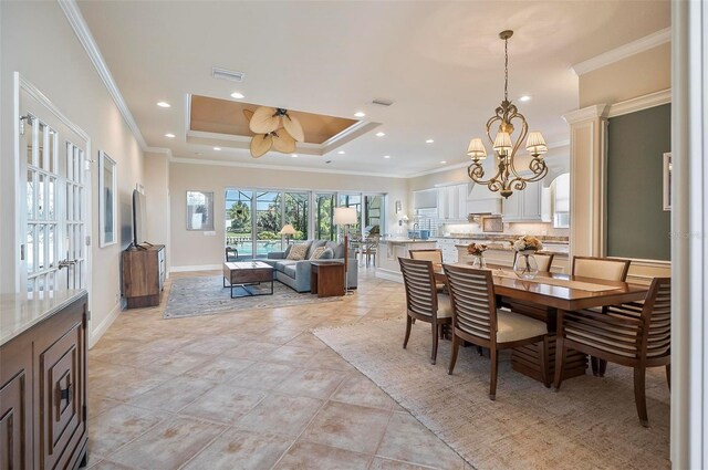 tiled dining space with a raised ceiling, ornamental molding, and ceiling fan with notable chandelier