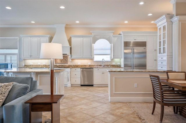 kitchen with crown molding, light stone counters, appliances with stainless steel finishes, and white cabinetry