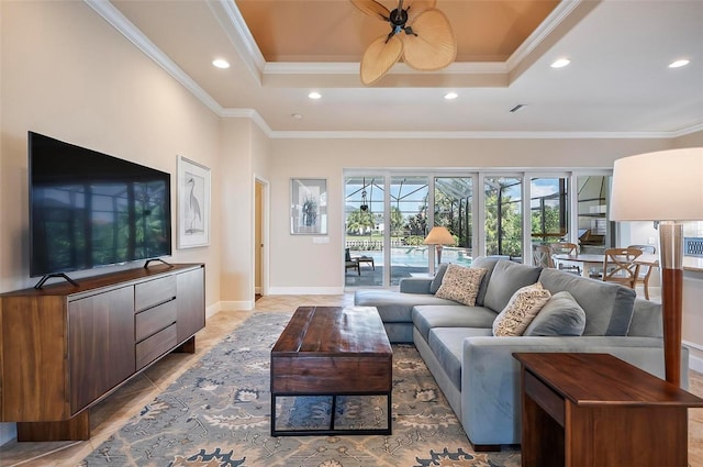 living room with a tray ceiling, ceiling fan, and crown molding