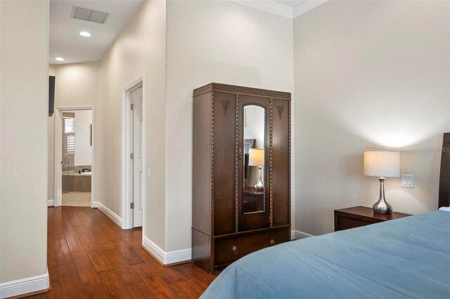 bedroom with crown molding, dark hardwood / wood-style flooring, and connected bathroom