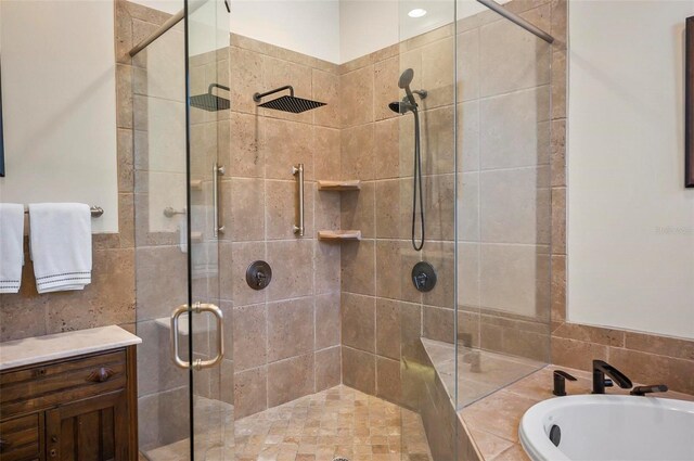 bathroom with tile walls, independent shower and bath, and vanity