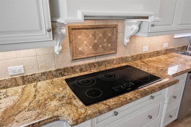 kitchen with black electric cooktop, light stone counters, white cabinets, and tasteful backsplash