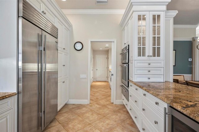 kitchen featuring dark stone counters, appliances with stainless steel finishes, and white cabinets