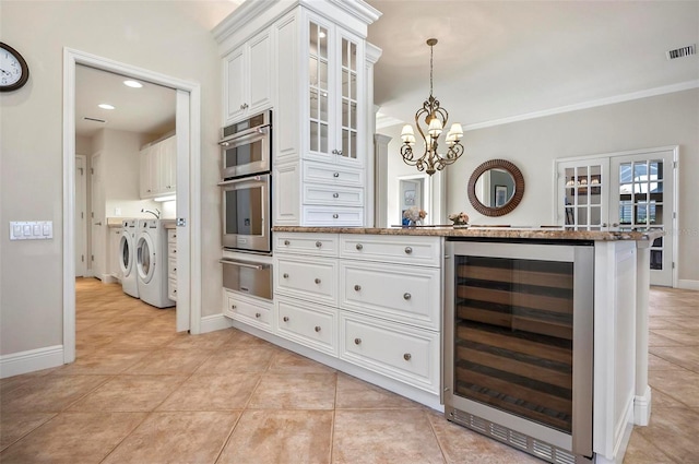 kitchen featuring white cabinets, stainless steel double oven, decorative light fixtures, washing machine and clothes dryer, and wine cooler