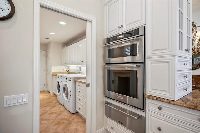 kitchen with washer and dryer, stainless steel double oven, dark stone countertops, and white cabinets