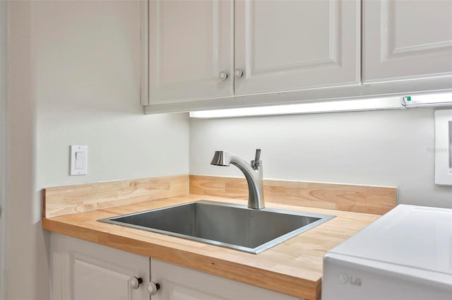 kitchen featuring white cabinets, sink, and wooden counters