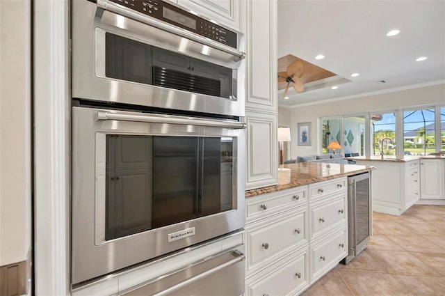 kitchen with white cabinetry, light tile patterned floors, wine cooler, light stone counters, and double oven