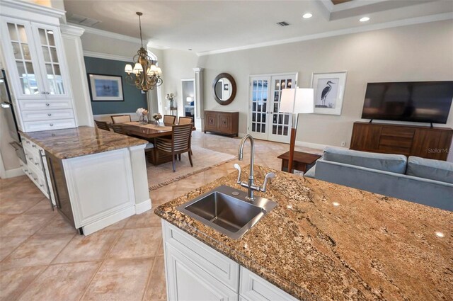 kitchen featuring pendant lighting, dark stone counters, sink, and white cabinets