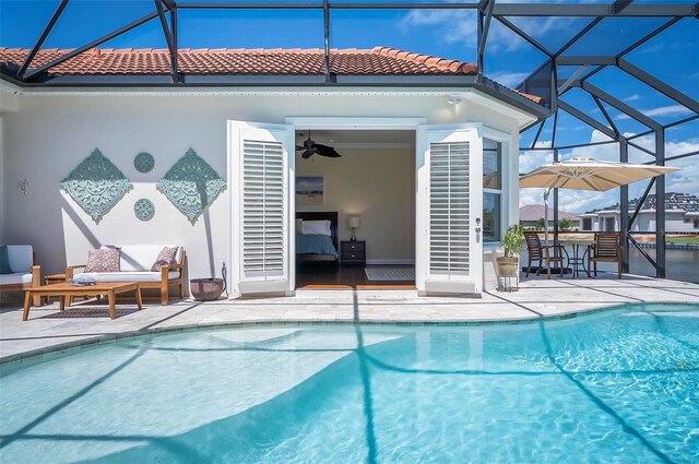 view of swimming pool featuring glass enclosure, ceiling fan, and a patio