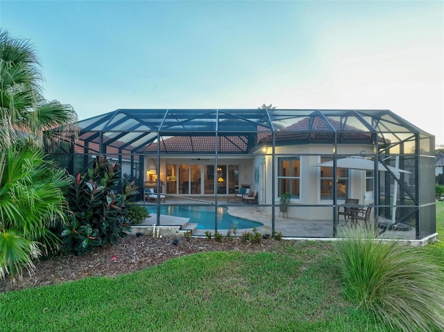 back of property with a patio area, a yard, and a lanai