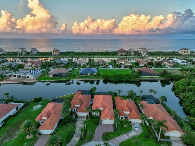 aerial view at dusk featuring a water view