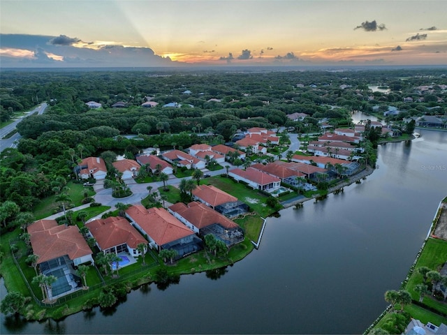 aerial view at dusk featuring a water view