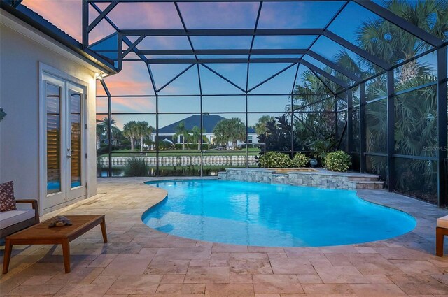 pool at dusk featuring a patio area, french doors, pool water feature, and a lanai