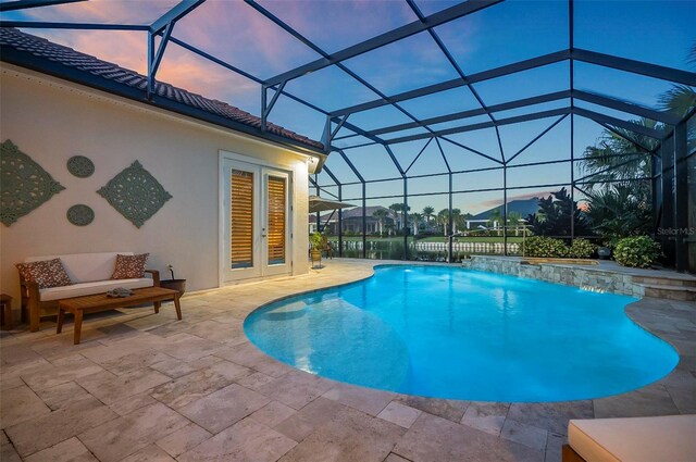 pool at dusk with glass enclosure, pool water feature, and a patio area