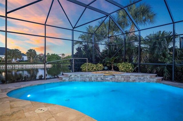 pool at dusk with a lanai, a water view, and pool water feature