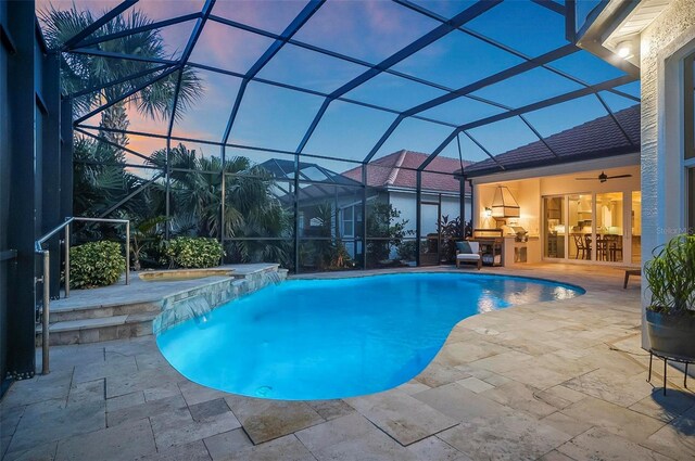 pool at dusk with pool water feature, ceiling fan, a patio, and glass enclosure