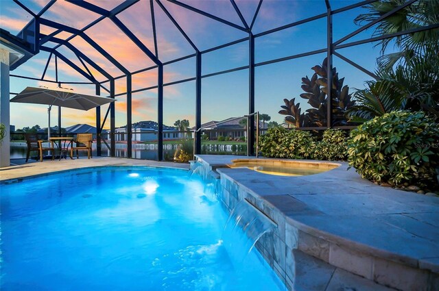 pool at dusk with a water view, pool water feature, a patio, and a lanai