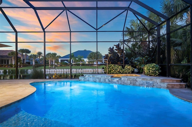 pool at dusk featuring a water view, pool water feature, a lanai, and a patio area