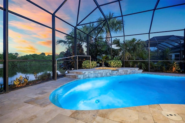 pool at dusk featuring a water view, a patio area, and a lanai