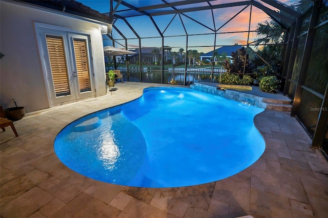 pool at dusk featuring a patio area, pool water feature, a water view, and a lanai