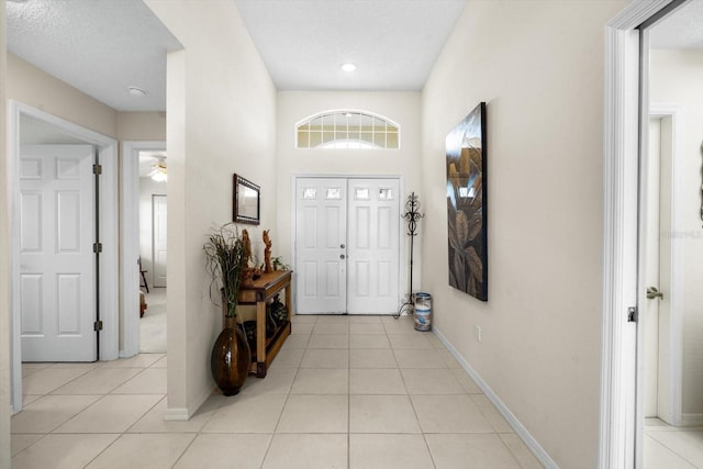 tiled entrance foyer with a textured ceiling and ceiling fan