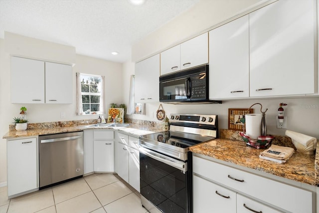 kitchen with light stone counters, stainless steel appliances, white cabinetry, sink, and light tile patterned flooring