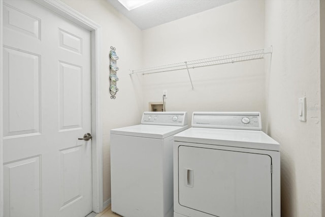 clothes washing area with washing machine and clothes dryer and a textured ceiling