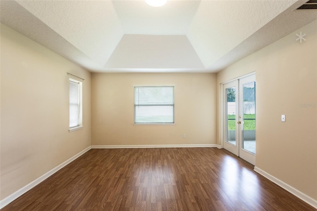 spare room with a textured ceiling, a raised ceiling, and dark hardwood / wood-style flooring