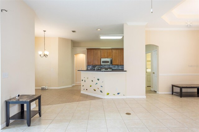 kitchen featuring pendant lighting, crown molding, backsplash, light tile patterned floors, and an inviting chandelier