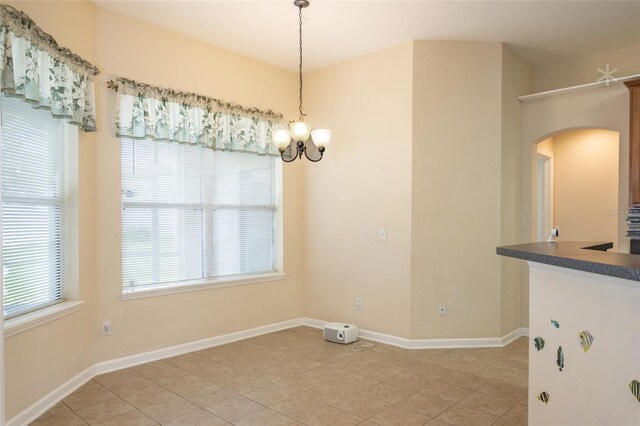 unfurnished dining area with light tile patterned floors and a chandelier