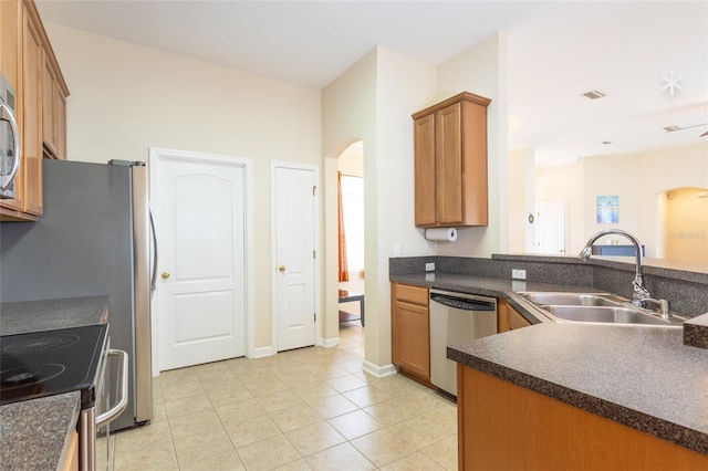 kitchen with appliances with stainless steel finishes, light tile patterned floors, sink, and kitchen peninsula