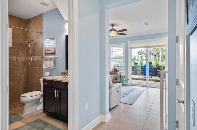 bathroom featuring vanity, a tile shower, tile patterned flooring, toilet, and ceiling fan