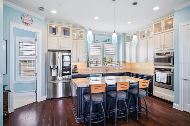 kitchen with light stone counters, stainless steel appliances, dark hardwood / wood-style flooring, sink, and a kitchen island