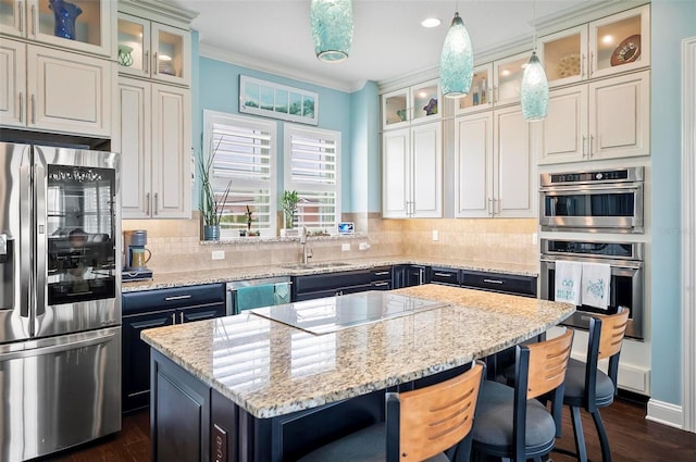 kitchen featuring pendant lighting, a kitchen island, stainless steel appliances, and light stone countertops