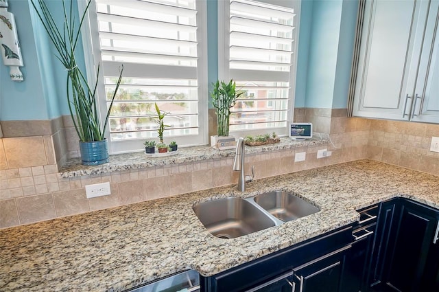 kitchen with a wealth of natural light, sink, and light stone countertops