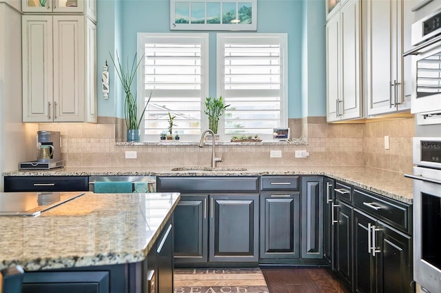 kitchen featuring dark hardwood / wood-style floors, sink, stainless steel oven, decorative backsplash, and light stone counters