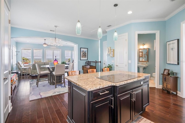 kitchen featuring dark wood-type flooring, pendant lighting, a kitchen island, and ornamental molding