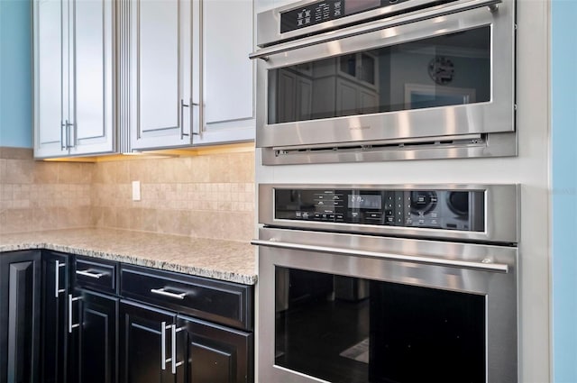 kitchen with stainless steel oven, tasteful backsplash, and light stone countertops