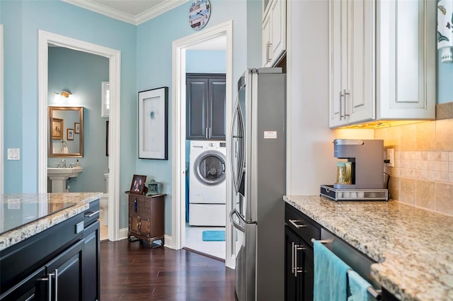 kitchen with stainless steel refrigerator, white cabinetry, dark hardwood / wood-style flooring, light stone countertops, and washer / dryer