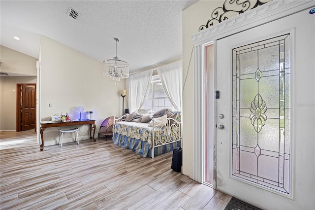 bedroom featuring vaulted ceiling, light hardwood / wood-style flooring, a notable chandelier, access to exterior, and a textured ceiling