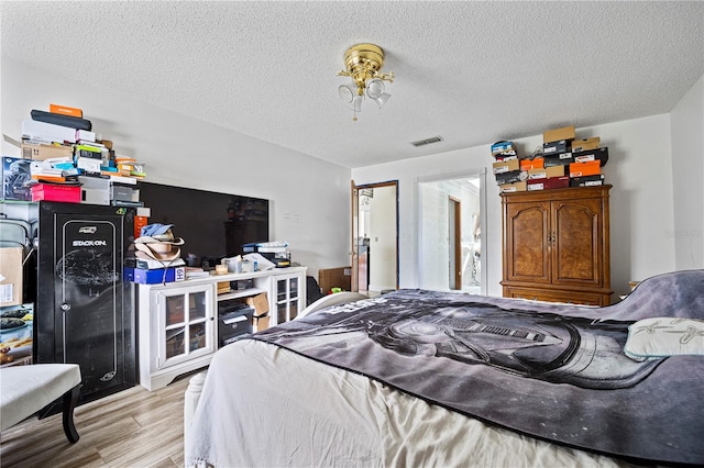 bedroom with hardwood / wood-style floors and a textured ceiling