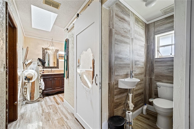 bathroom with a skylight, hardwood / wood-style floors, toilet, and vanity