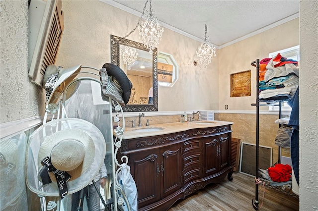 bathroom featuring ornamental molding, vanity, a textured ceiling, a chandelier, and wood-type flooring