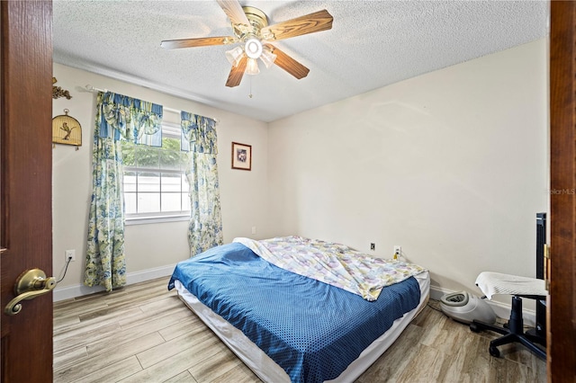 bedroom with a textured ceiling, ceiling fan, and light wood-type flooring