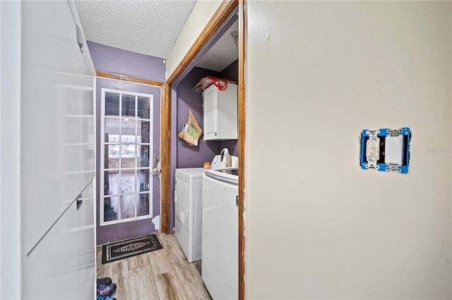 laundry room with separate washer and dryer, a textured ceiling, cabinets, and light hardwood / wood-style floors