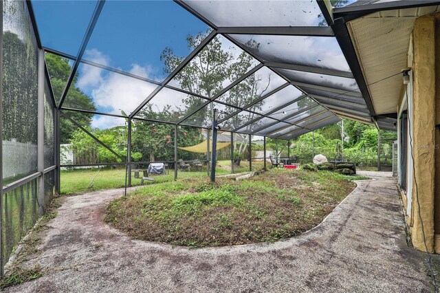 view of yard with glass enclosure and a patio area