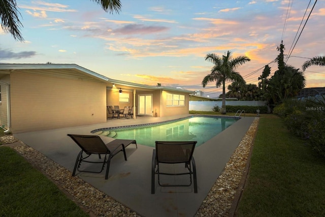 pool at dusk with a yard and a patio area