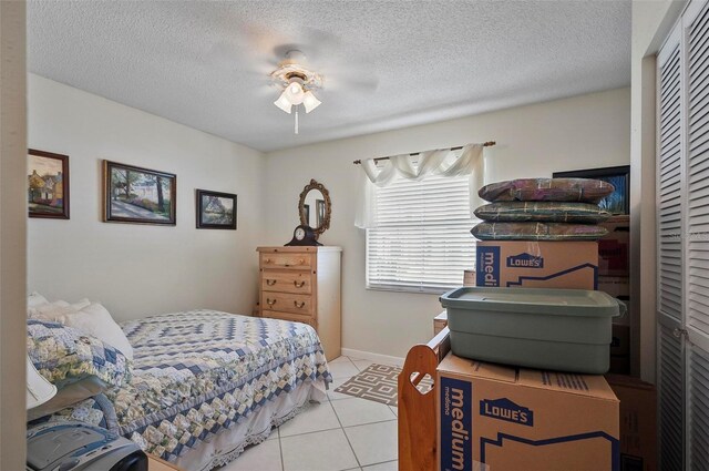 tiled bedroom featuring a textured ceiling, ceiling fan, and a closet