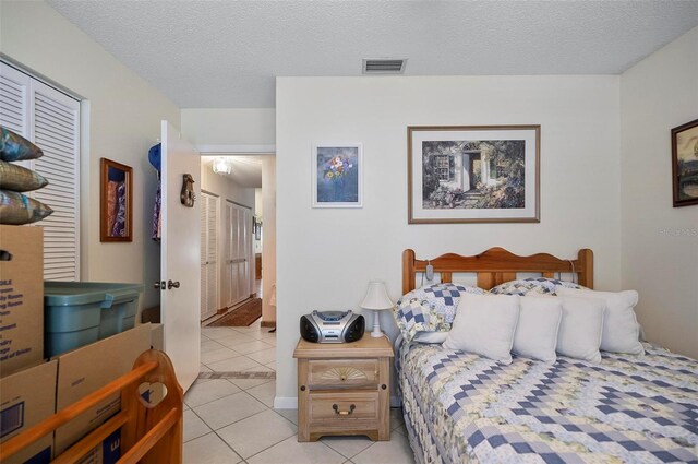 tiled bedroom with a closet and a textured ceiling