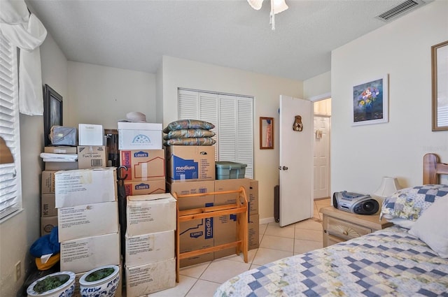 tiled bedroom with a textured ceiling and a closet